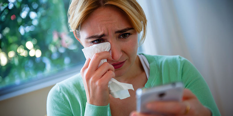 Crying Caucasian woman using cell phone