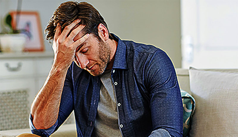 Man sitting alone at home looking sad and distraught