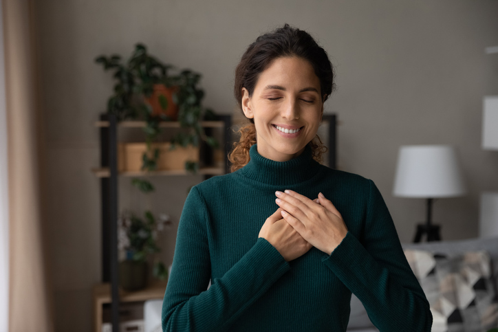 Happy Latin woman hold hands on heart feeling grateful