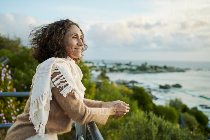 Smiling mature woman looking out at the sunset over the ocean
