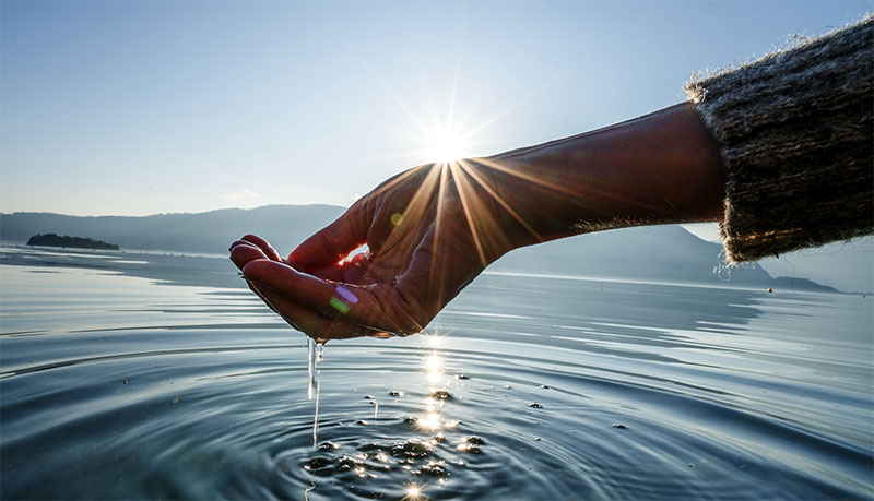 Human hand cupped to catch fresh water from lake