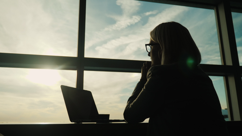 A woman in a business suit looks out the window of her office. Concept &#8211; look ahead in business