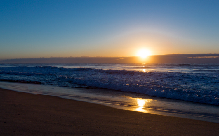 Sunrise with rising sun on morning beach