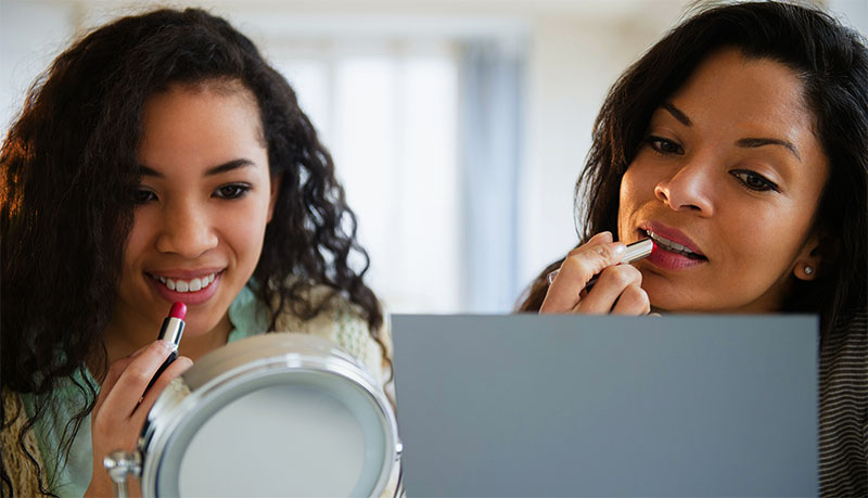 Mother and daughter applying makeup