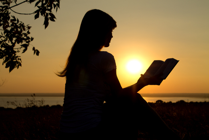 silhouette of a girl reading at sunset