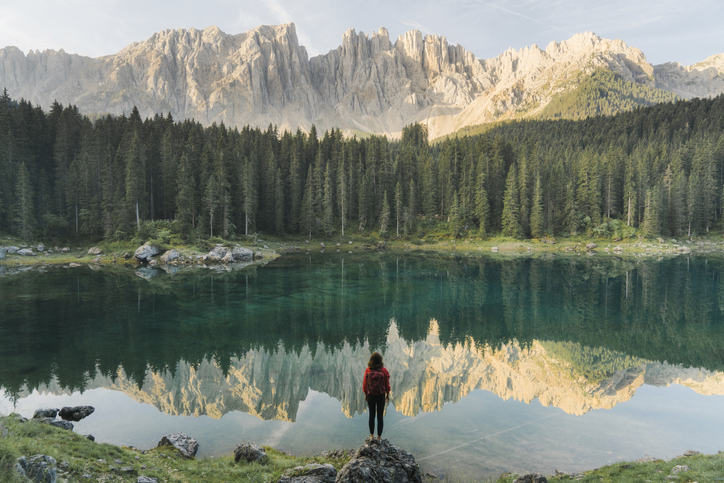 Woman standing and looking at  Lago di Carezza in Dolomites