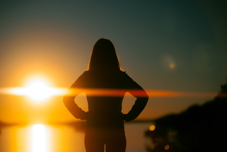 Silhouette of a Woman Looking at a River During Sunset