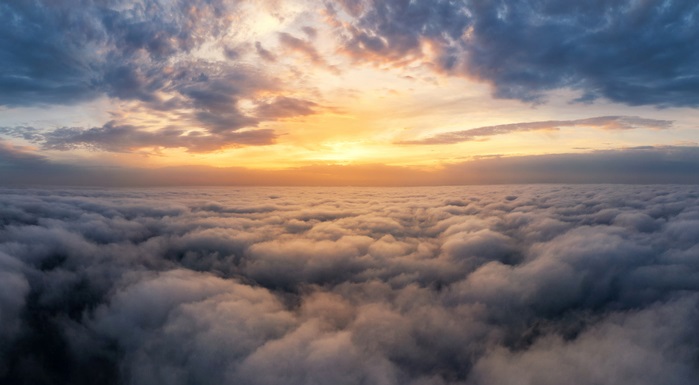 Beautiful dramatic sunset sky above fluffy clouds early in the morning. Drone view.