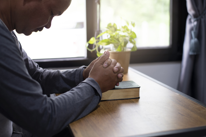 Prayer and bible concept. Asian senior man praying, hope for peace the world and free from coronavirus, Hand in hand together, believes and faith in christian religion at home.