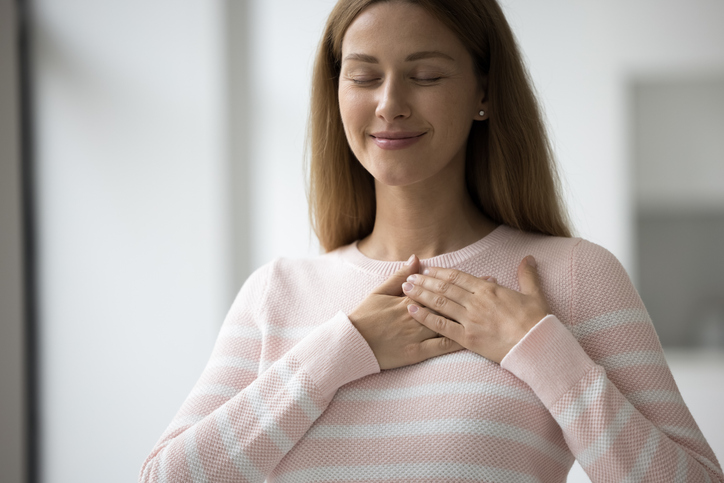 Happy volunteer woman in casual applying stacked hands to chest