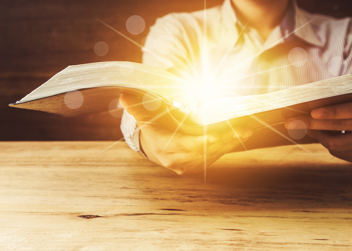 Close Up Of A Man Holding Holy Bible With Star and Bokeh Light Effected on Wood table