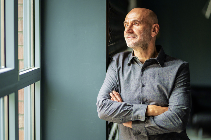 Portrait of thinking business man standing with arms crossed at the office