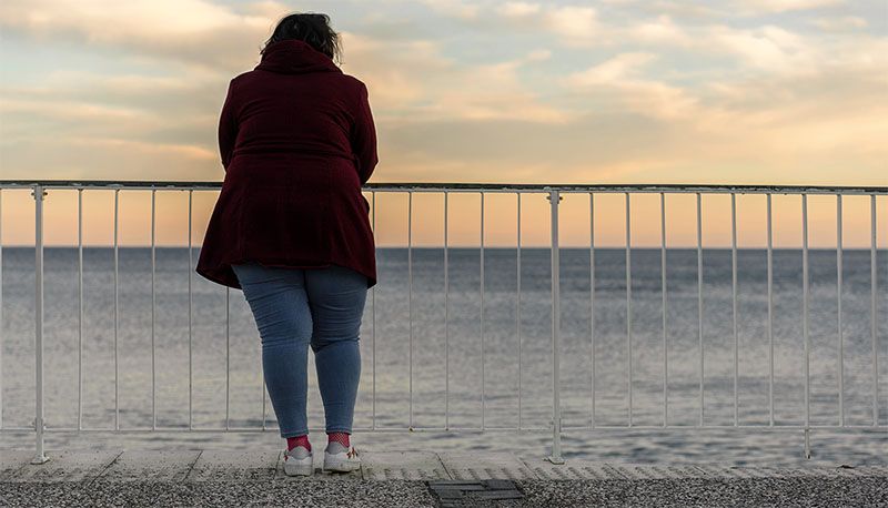 Young fat woman standing alone on the beach