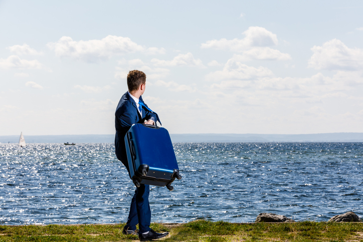 Businessman standing with suitcase at seaside