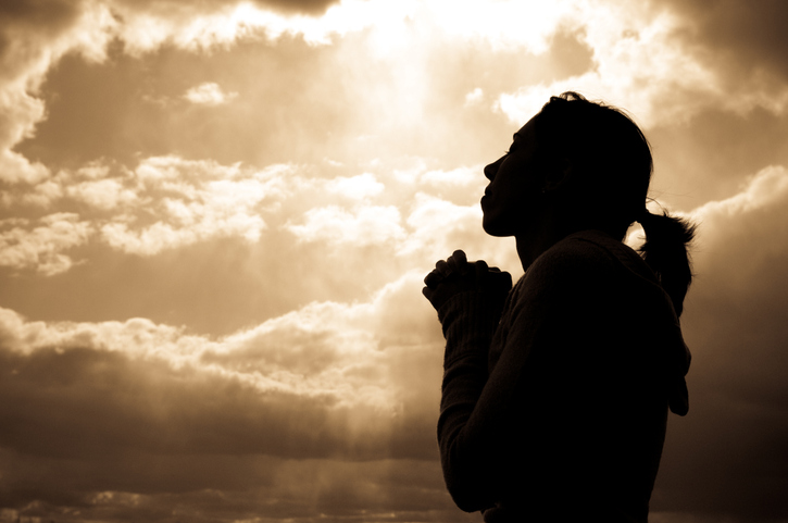 Silhouette of a woman looking at the sky, praying