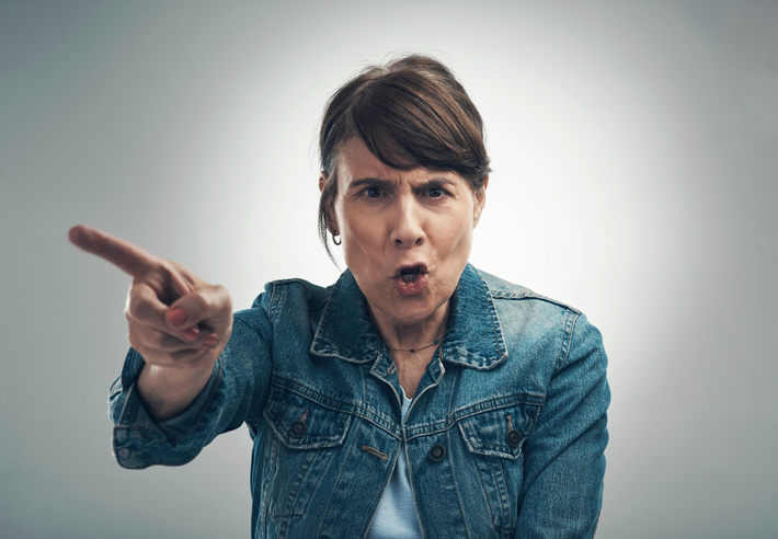 Studio portrait of a senior woman yelling against a grey background