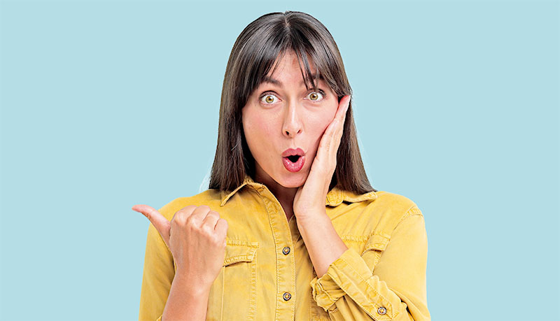 Special promotion. Surprised woman pointing at something on light blue background, space for text