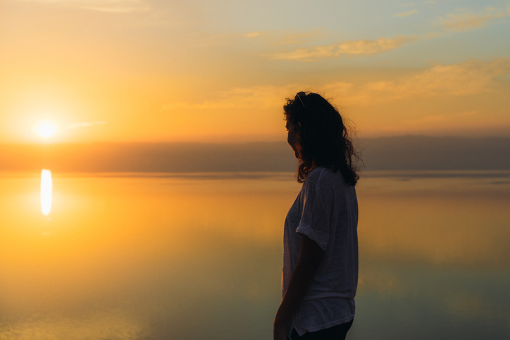 Silhouette of woman contemplating the scenic sunset above the Dead Sea in Jordan