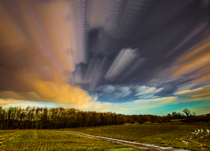 timelapse movement of clouds towards woods across a field