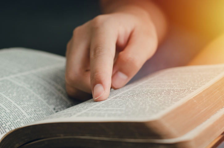 A young woman pointing out the verses of the Scriptures that are true to life. while reading the bible In the morning by the window sill