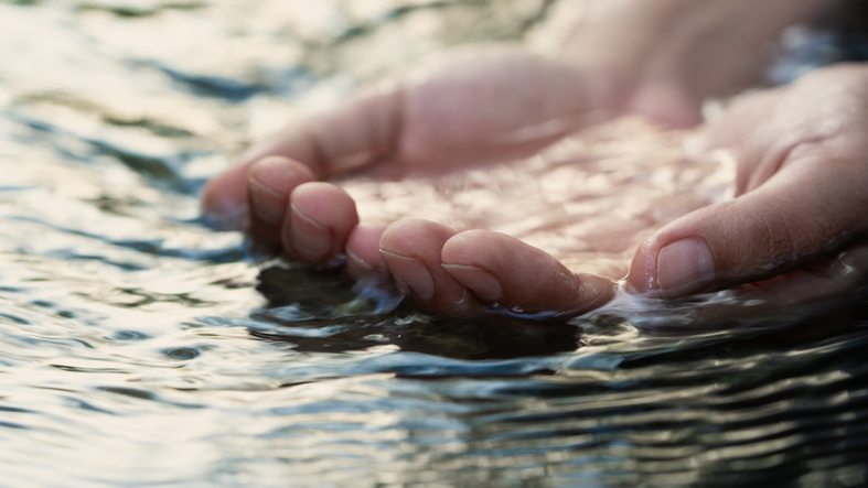 A female hand touching the river water