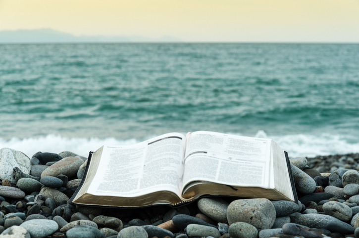 Bible open in front of the sea.