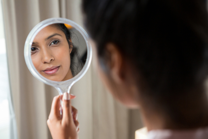 Woman reflecting on hand mirror