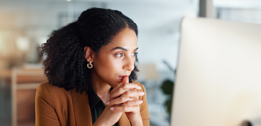 Woman at computer in office, thinking and reading email, feedback review or web article at digital agency. Internet, research and girl at tech startup networking, business schedule or admin project.