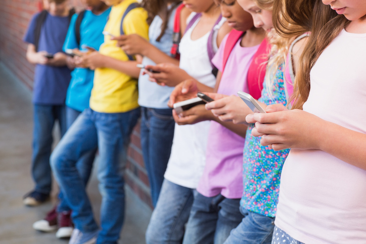 Cute pupils using mobile phone