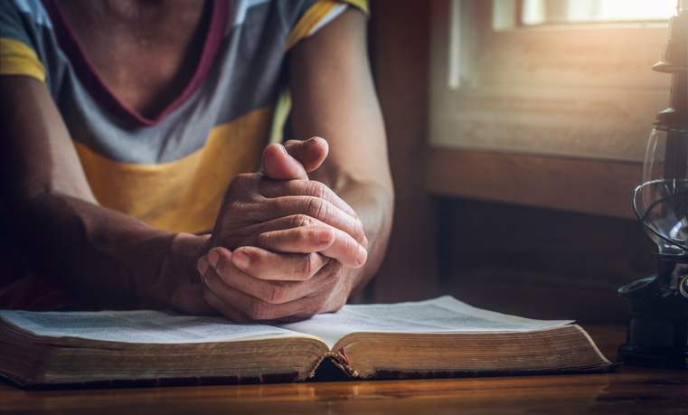 focus on a hands of old woman while praying on Bible, christian concept