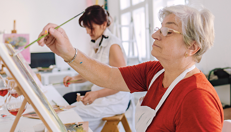 Senior woman painting in art class