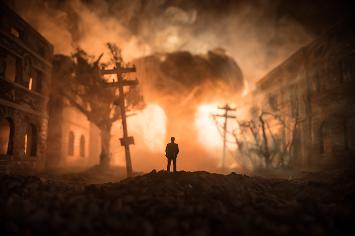 Artwork decoration. A man standing on a road of burnt up city. Apocalyptic view of city downtown as disaster film poster concept. Night scene. City destroyed by war.