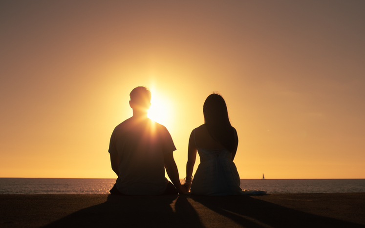 Couple watching beautiful sunset at the beach.