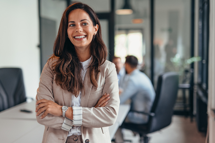 Smiling businesswoman standing confidently in modern office space.