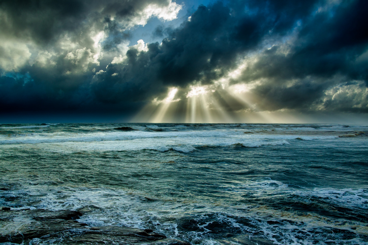 Sun rays poking through the dark stormy clouds in the pouring rain