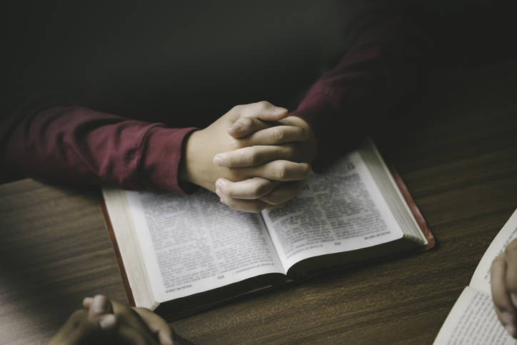 Christian group or family prayer together with a holy bible on a wooden table in church for worship to god in the morning. people pray with faith, Spirituality, and religion concept