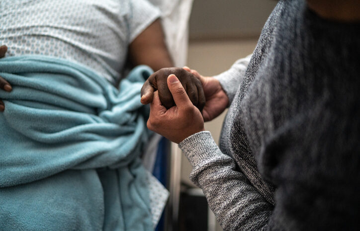 Son holding father&#8217;s hand at the hospital