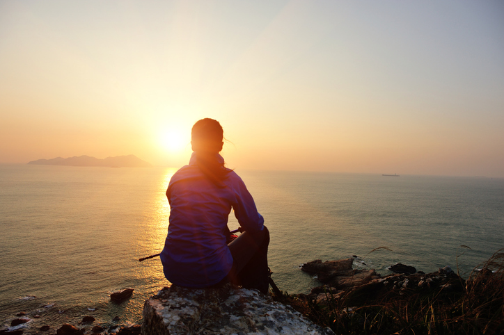 woman hiker sit on rock face the sunrise
