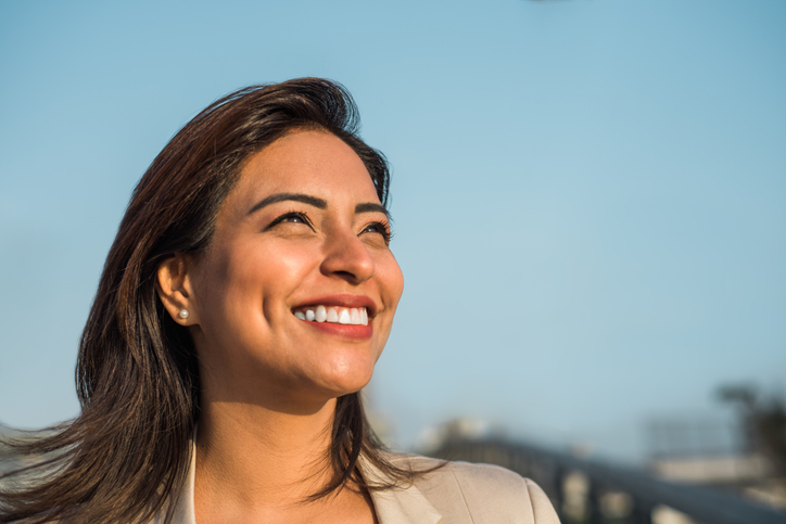 Close-up of a Latina woman smiling sideways. Copy space