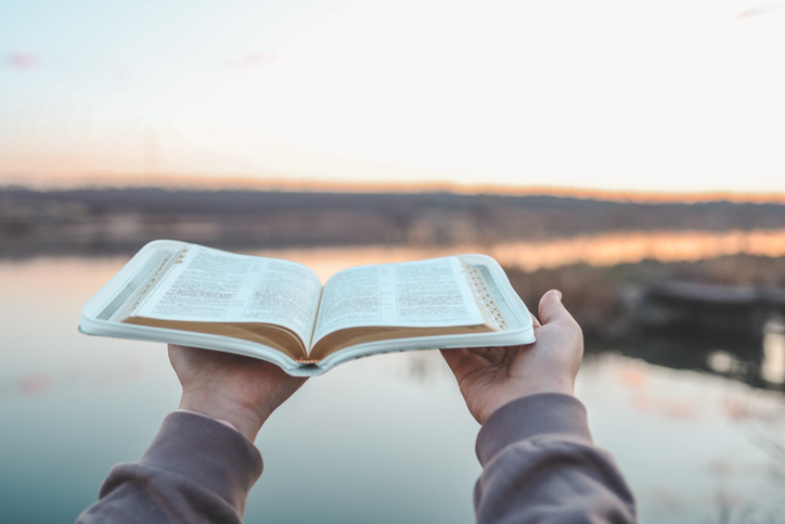 Bible in the hands of a girl, concept morning prayer in nature