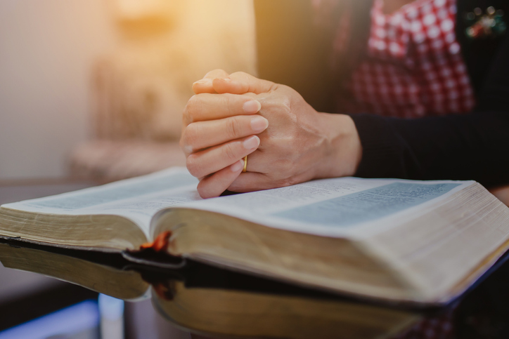 a woman prays on the holy bible