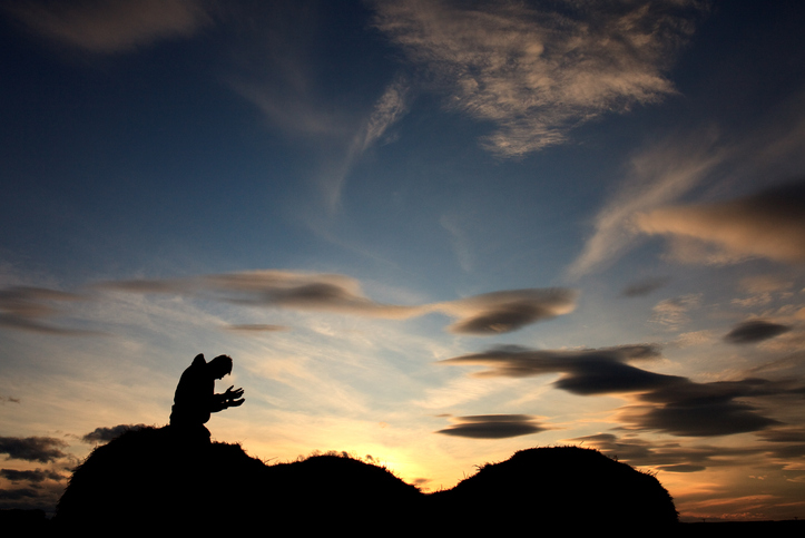 Silhouette of Man in Prayer Against Beautiful Sunset Sky