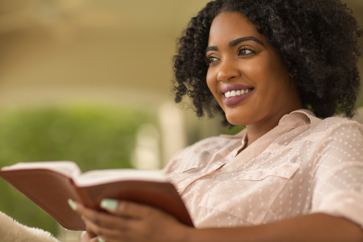 Woman smiling holding a book.