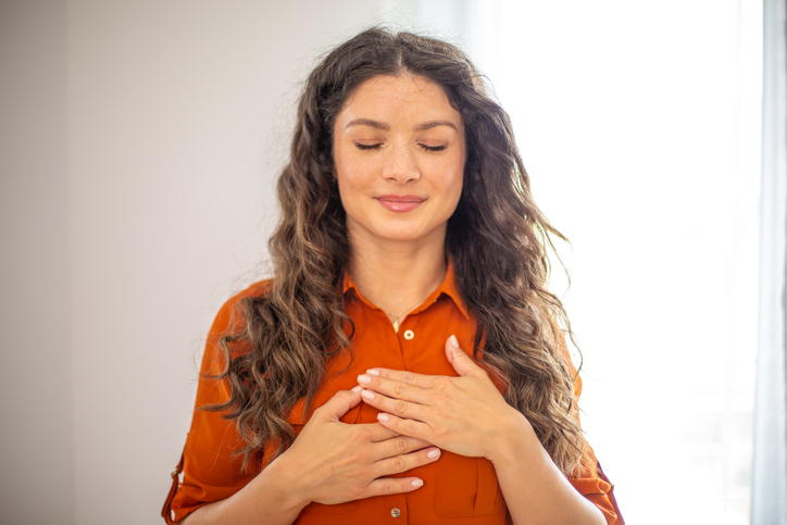 Serene woman expressing gratitude and hope with hands on chest