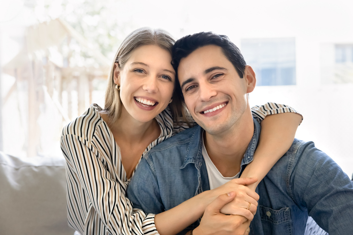 Happy young Latin couple in love hugging on home couch