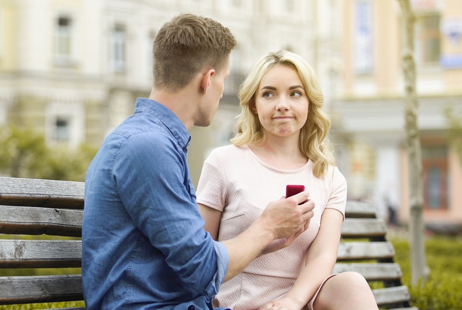Young woman rejecting boyfriends proposal, disappointed with engagement ring