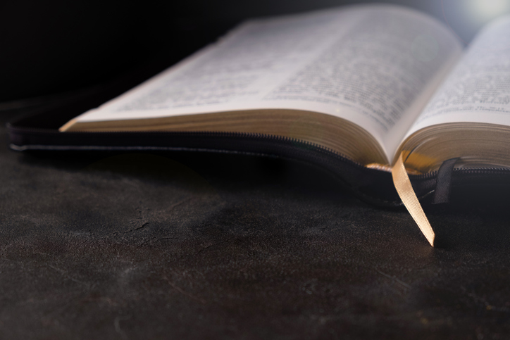 Open Bible on a dark table with light coming from above. Christianity concept. Holy Bible background.