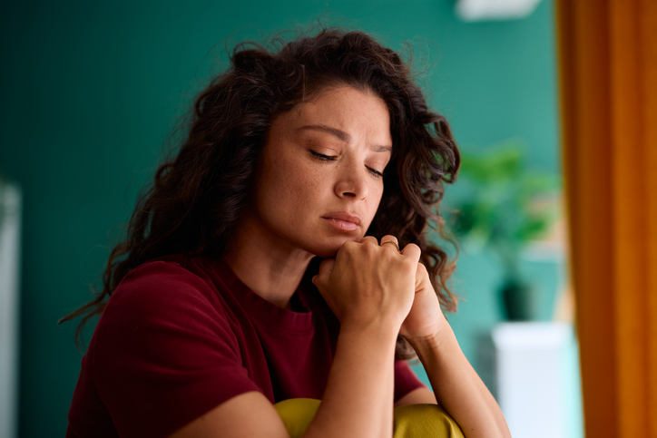Sad woman sitting alone at home, feeling lonely and depressed