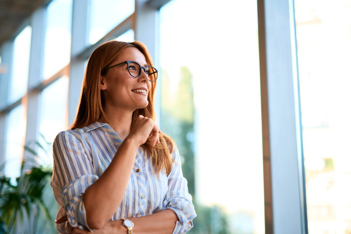 Businesswoman looking out the window and smiling, contemplating future opportunities