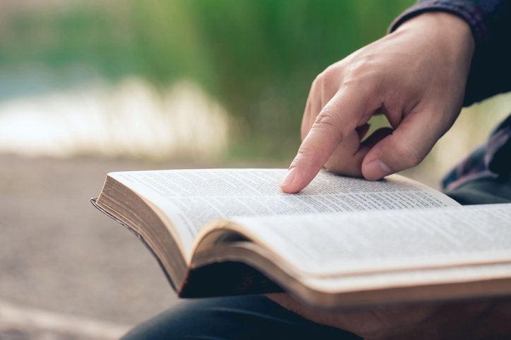 Close-up of man’s hands while reading the Bible outside.Sunday readings, Bible education. spirituality and religion concept.